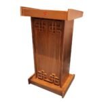 Front view of a premium teak wooden podium stand with intricate carved design elements & natural polish finish